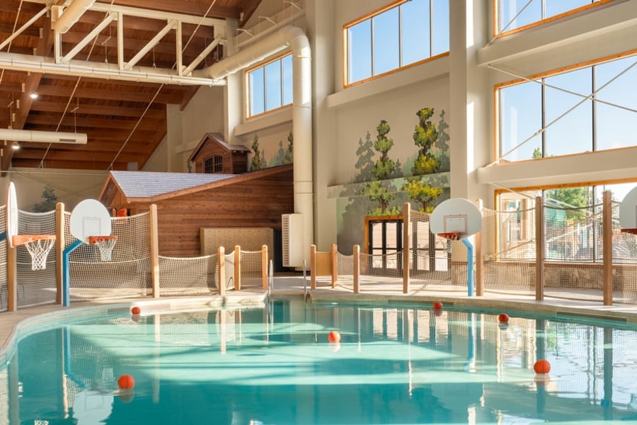family playing basketball in indoor pool 