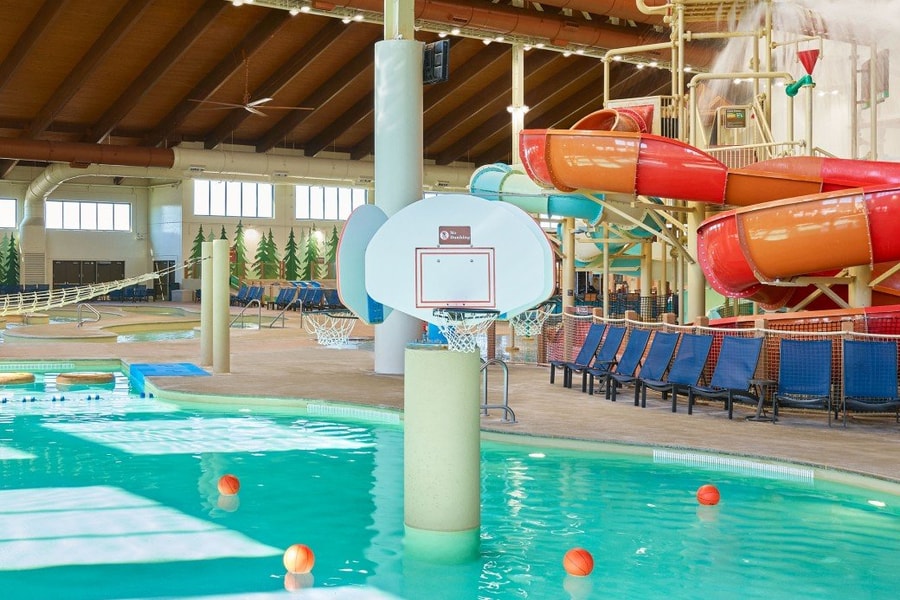 family playing basketball in indoor pool 