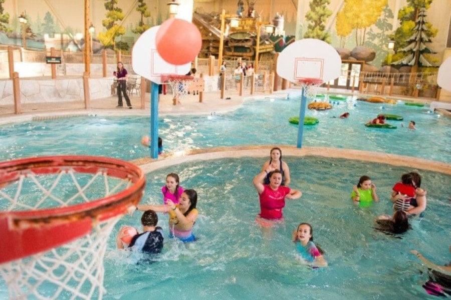 family playing basketball in indoor pool 