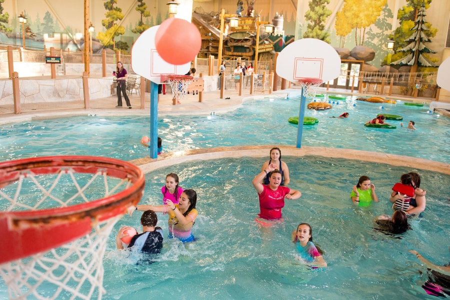 family playing basketball in indoor pool 