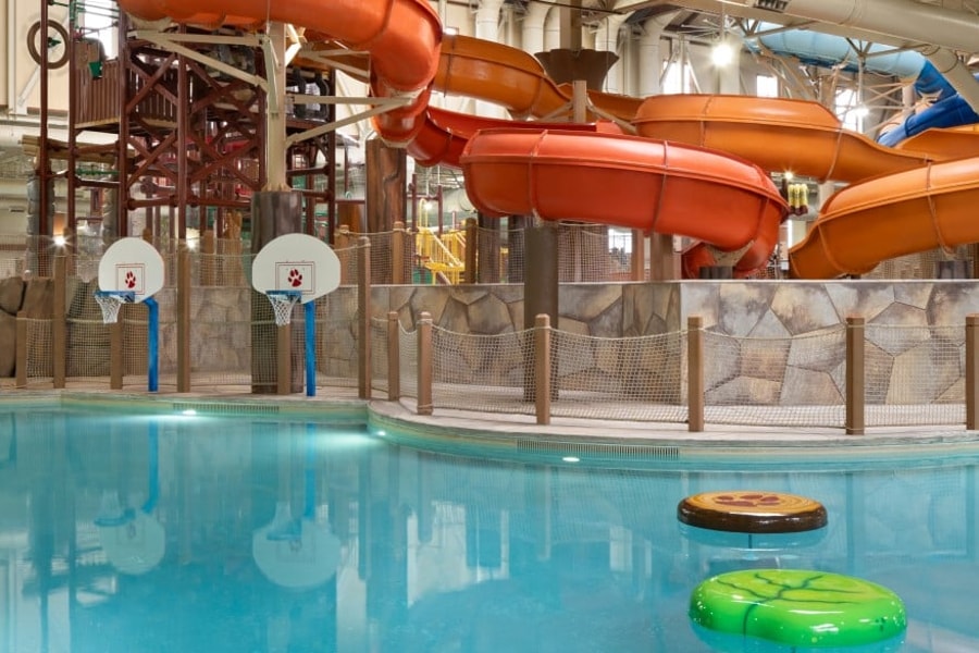 family playing basketball in indoor pool 