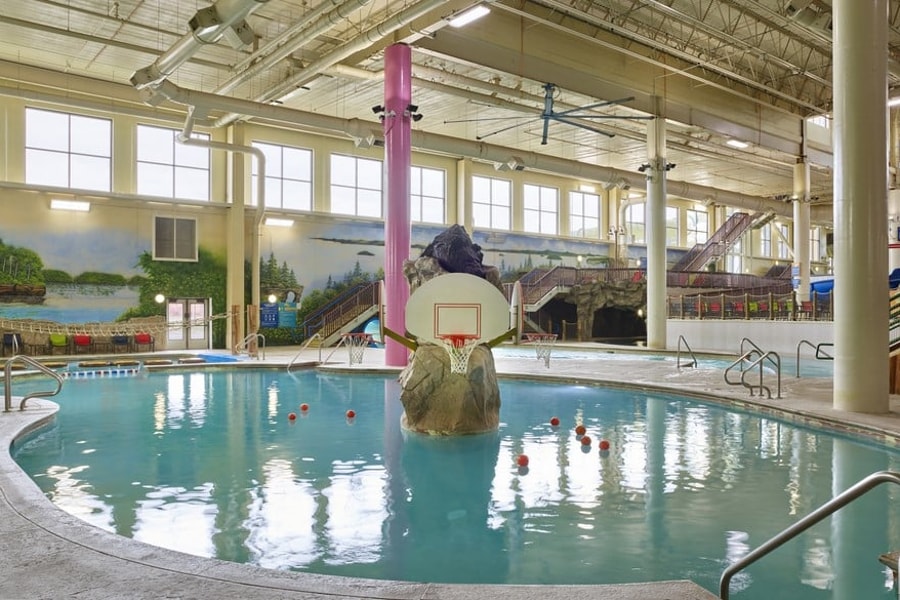 family playing basketball in indoor pool 
