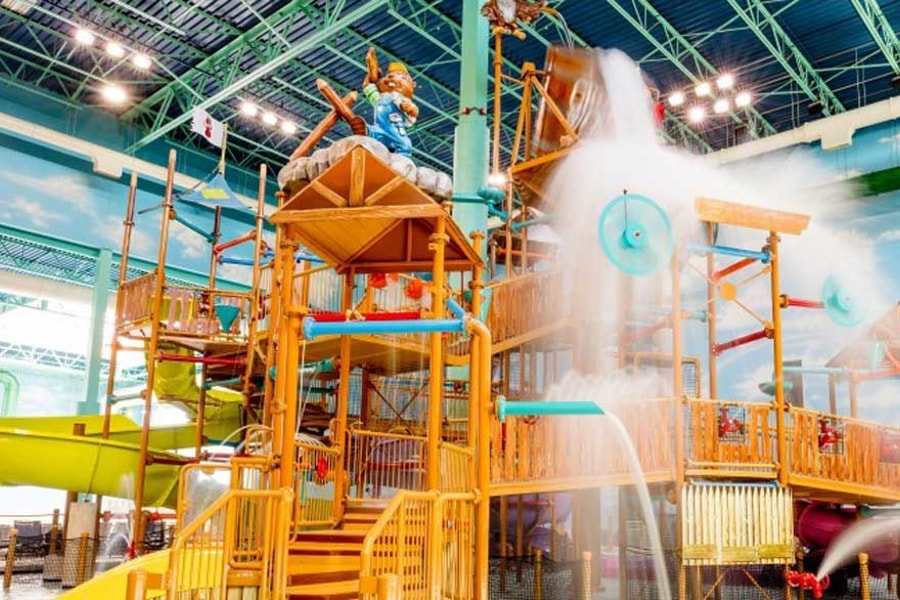 A wide shot of the  water treehouse as water splashes down from a bucket above the jungle gym