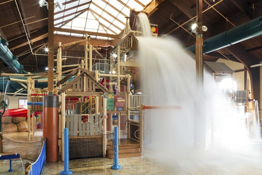 A wide shot of the  water treehouse as water splashes down from a bucket above the jungle gym