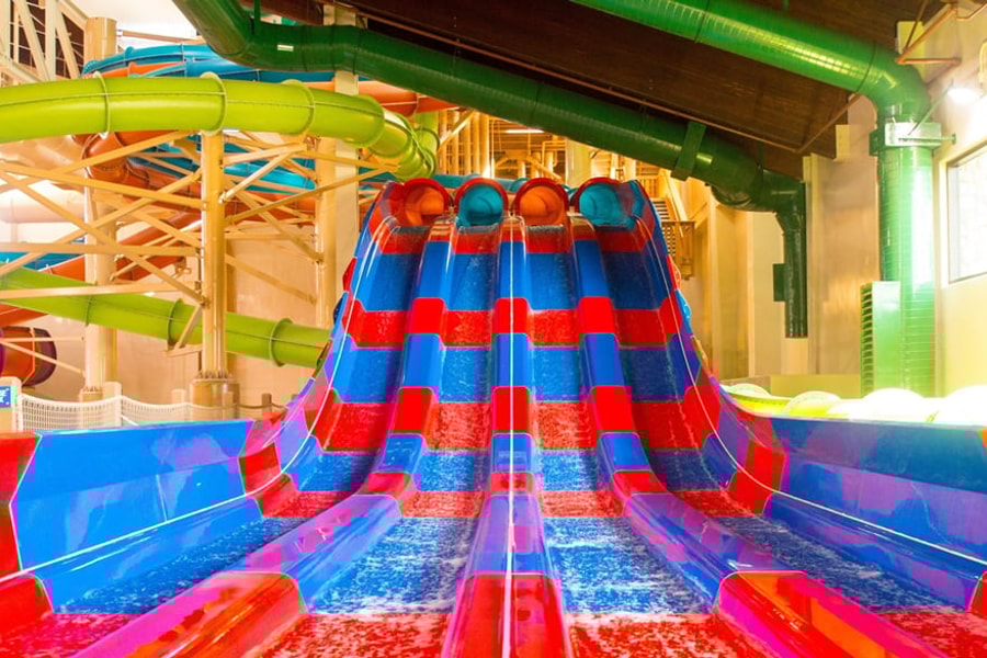 Two kids race down a waterslide laying on their stomaches 