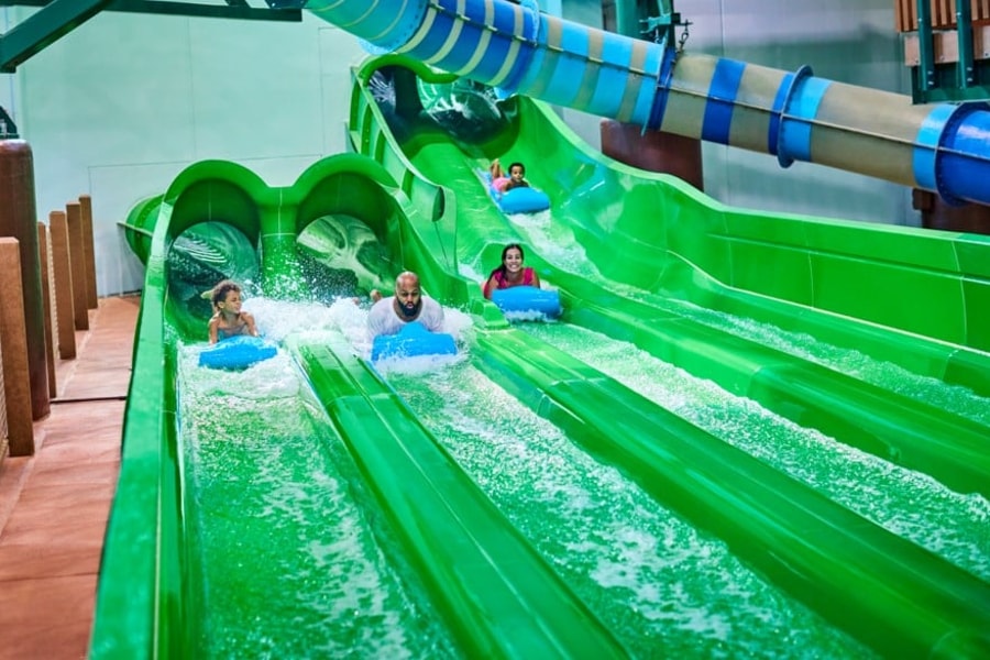 Guests race down a waterslide laying on their stomaches 