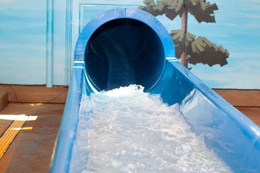 The end of a blue waterslide with water splashing out