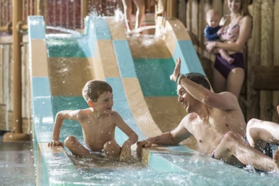 dad high fives his son as they come down a waterslide 