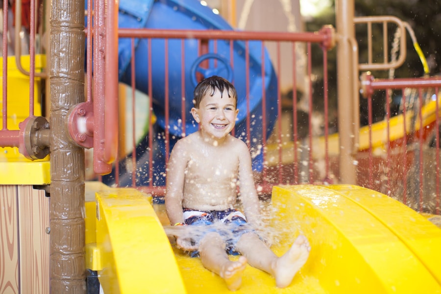 little boy about to go down a yellow kiddie slide