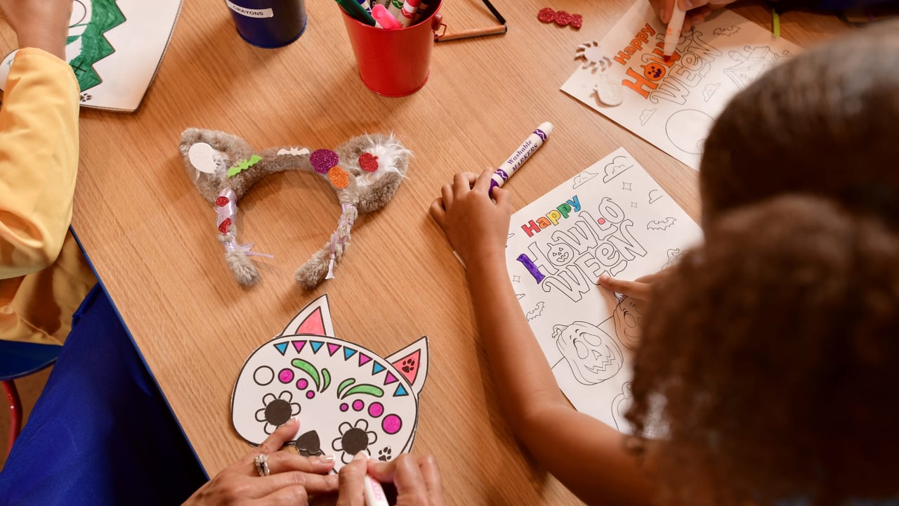 Children coloring Halloween pages and masks at craft table
