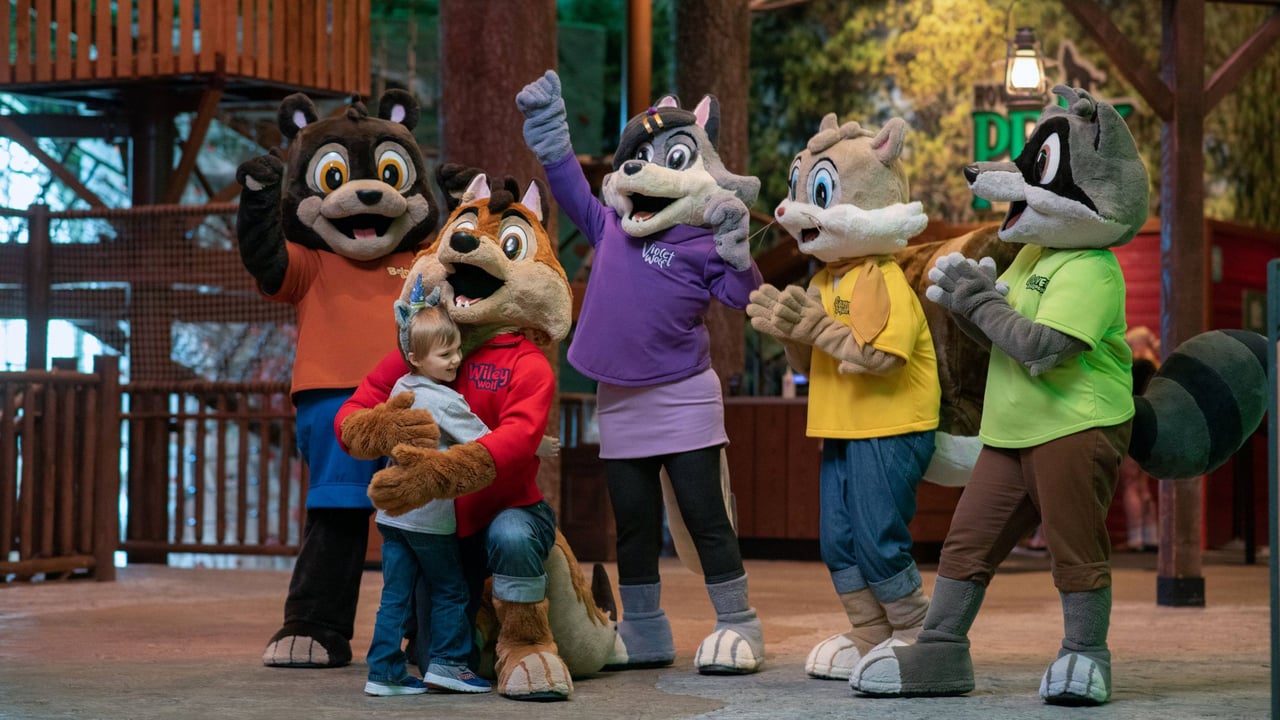 Five animal mascots posing with a child in a theme park