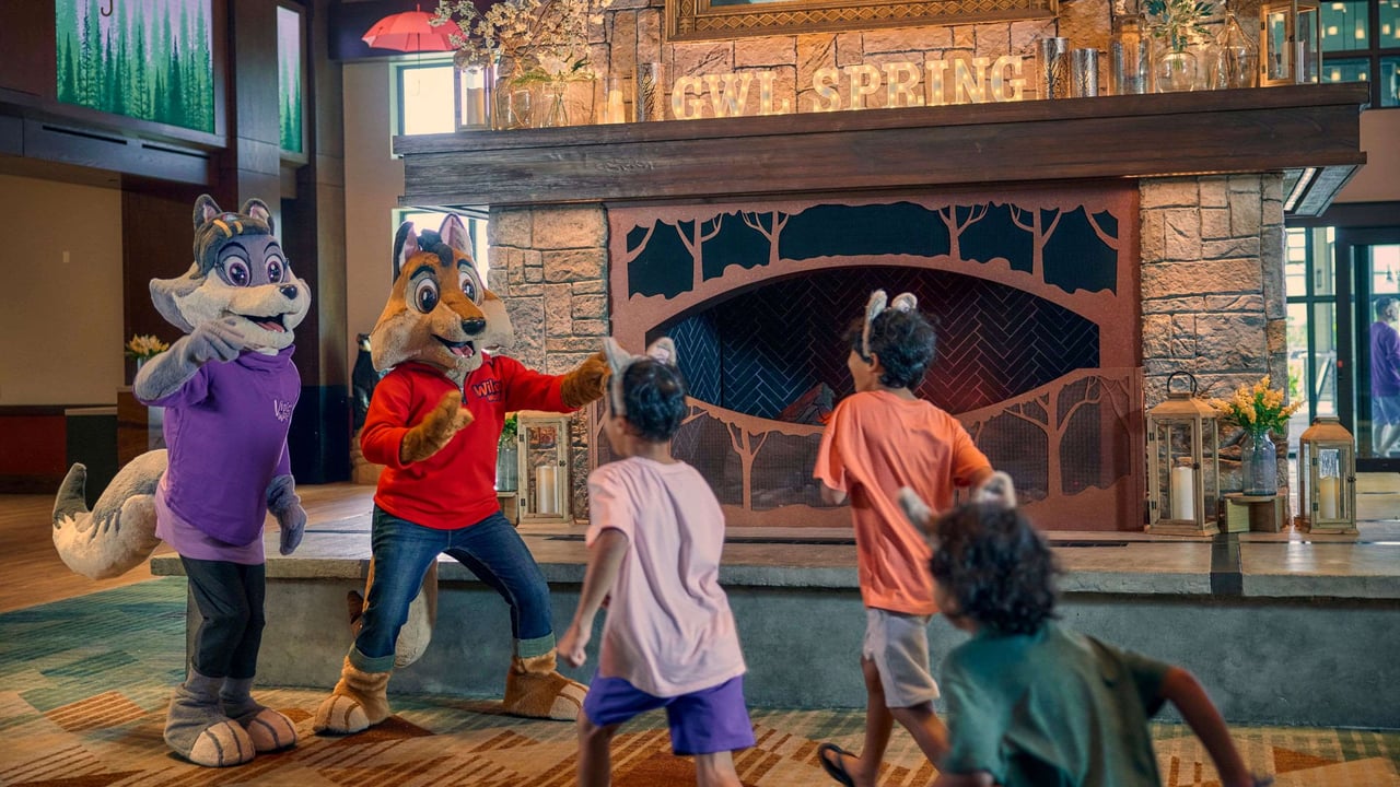 Mascots dancing with kids in front of a fireplace