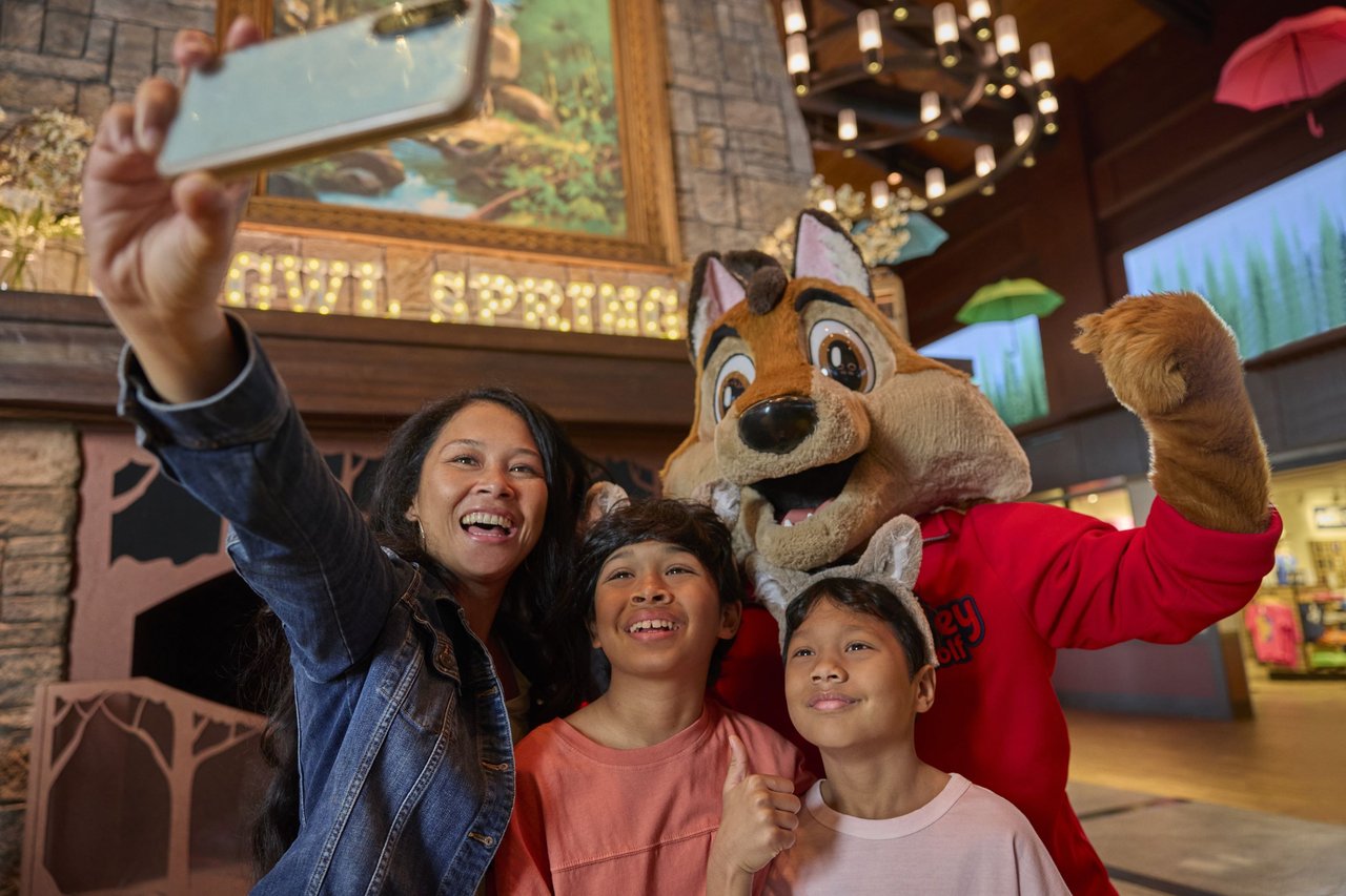 A family taking a selfie with a wolf mascot