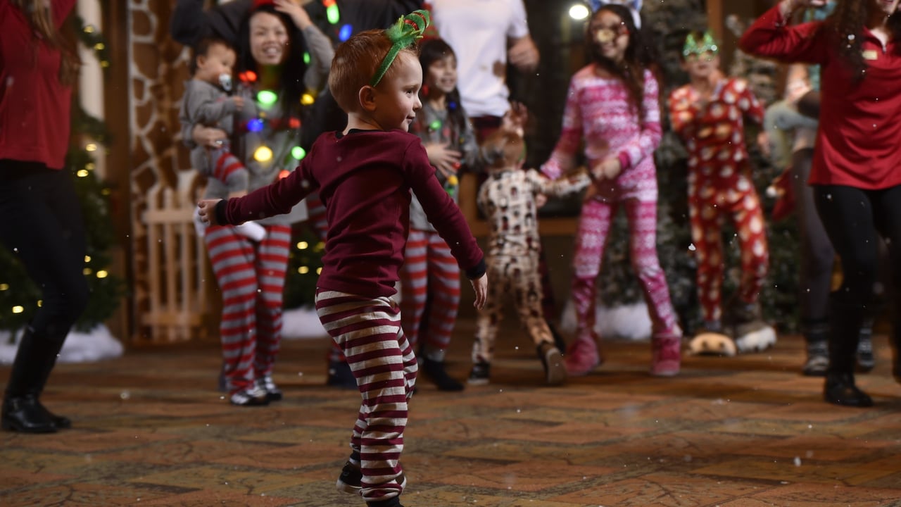 Child in holiday pajamas dancing with family at festive celebration