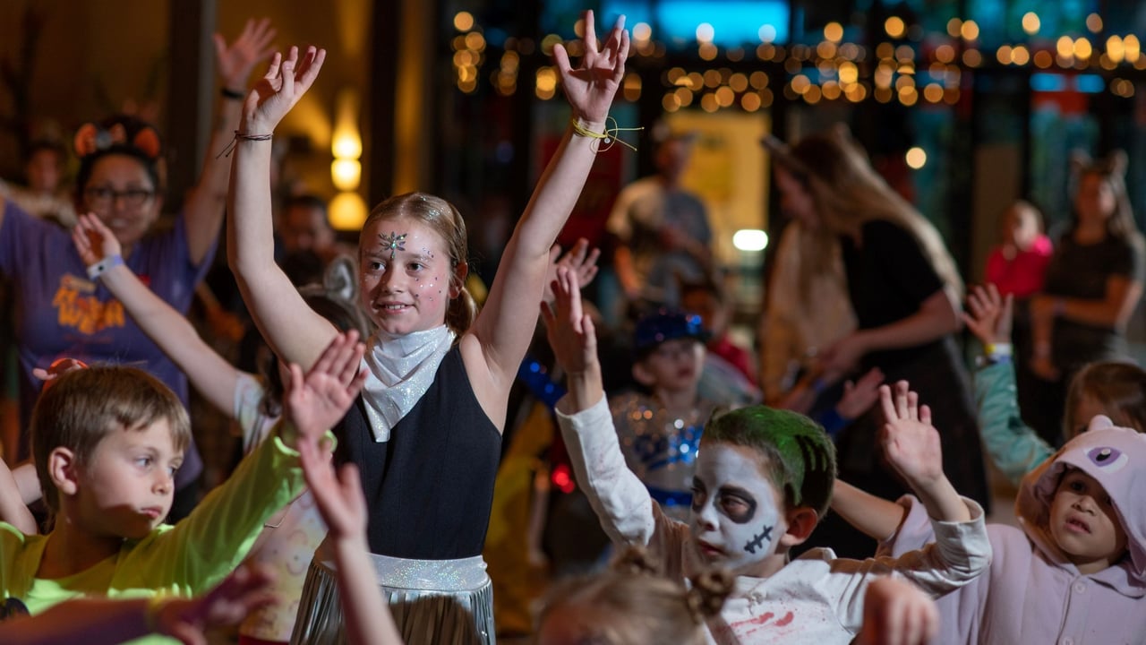 Children in costumes dancing with raised hands in a festive setting