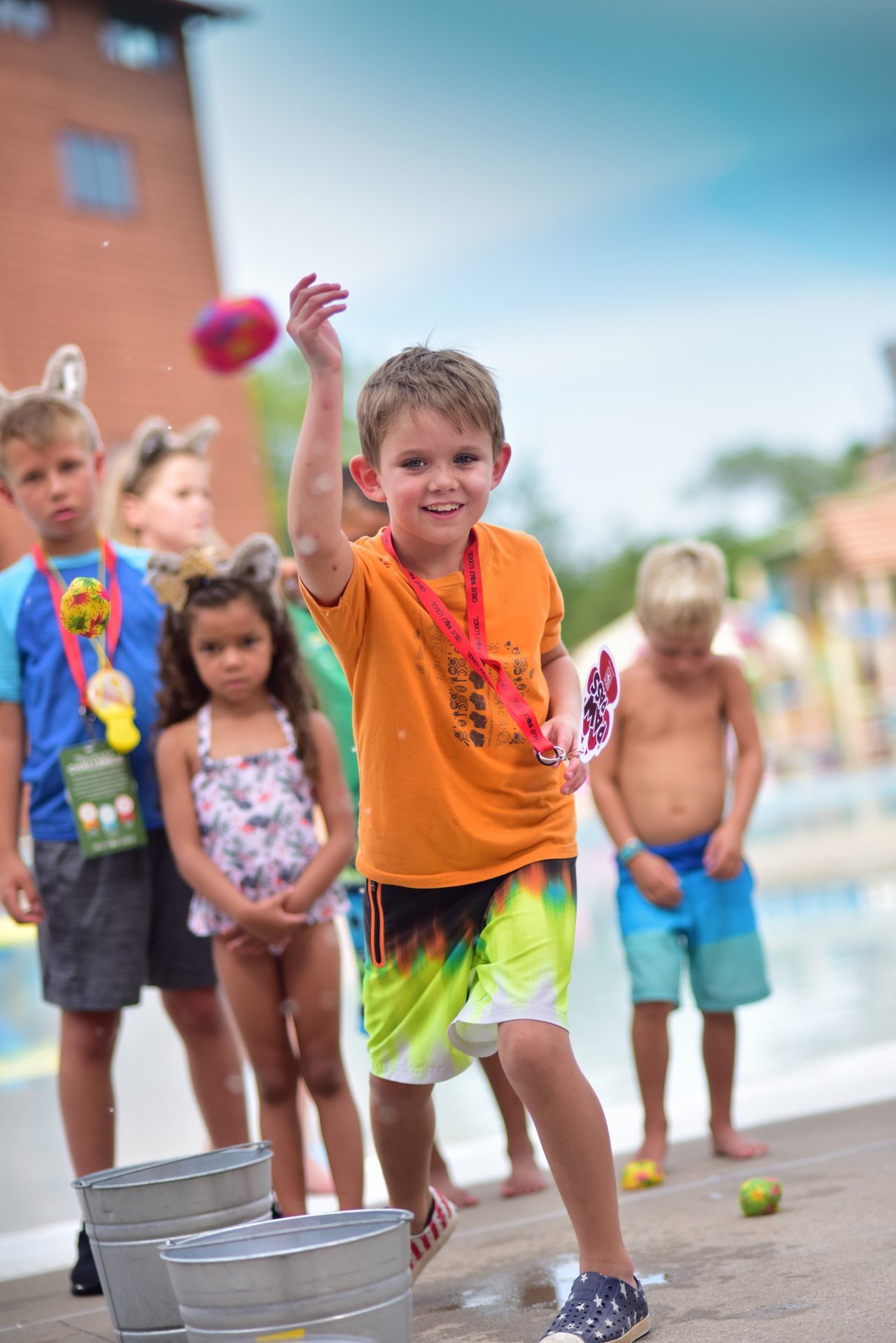 Child throwing water balloon during poolside activity