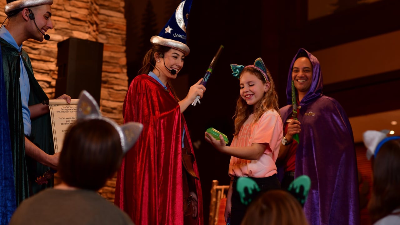 Girl smiling while receiving wand from woman in wizard costume