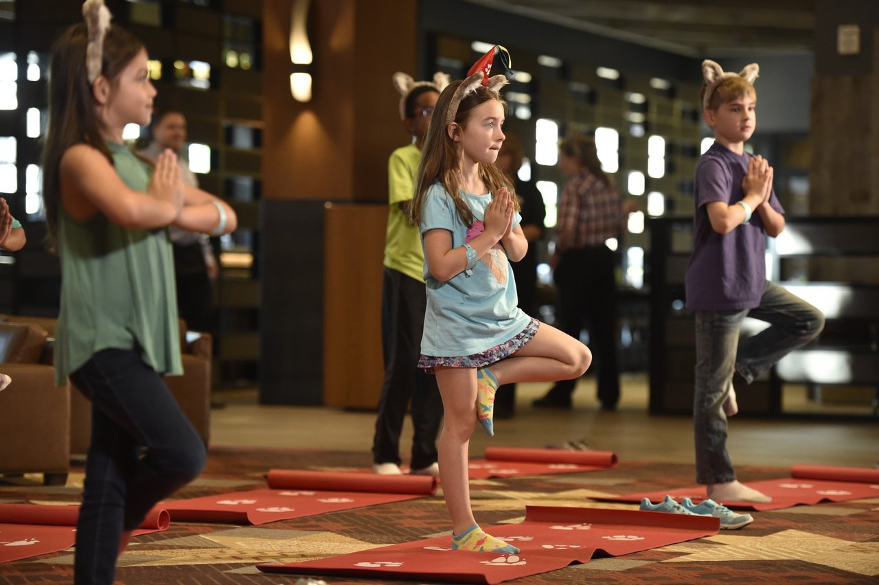 Children practicing yoga tree pose on red mats at Great Wolf Lodge