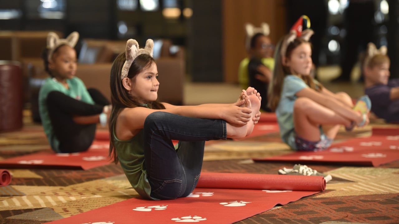 Children doing seated yoga pose on red mats at Great Wolf Lodge