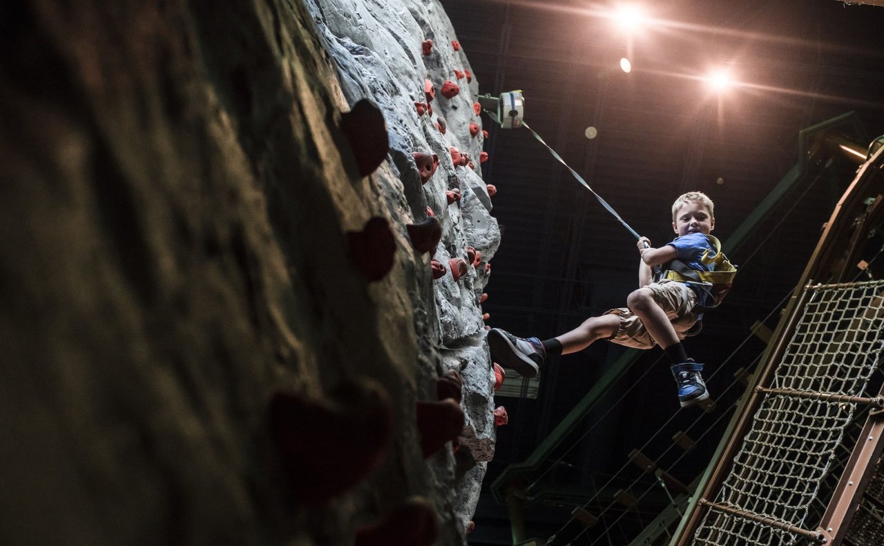 Child hanging by harness after climbing rock wall