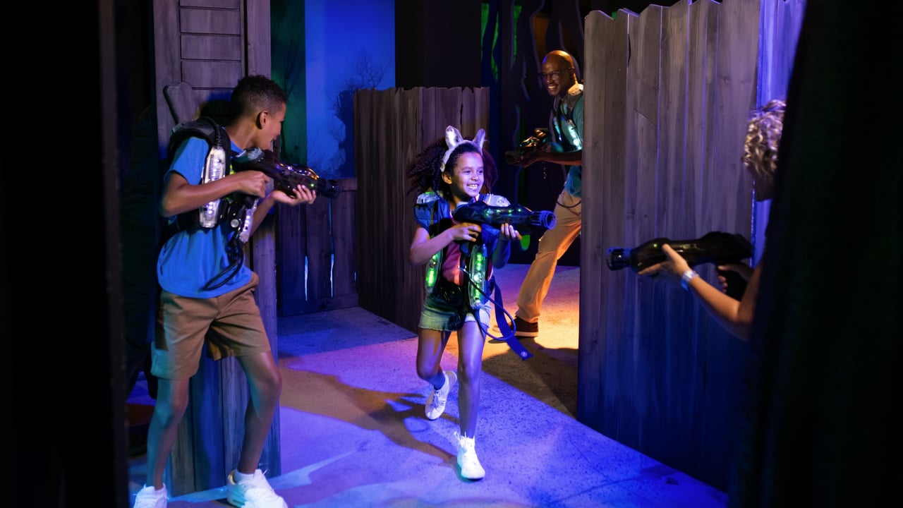 Family plays laser tag in a dark, glowing arena
