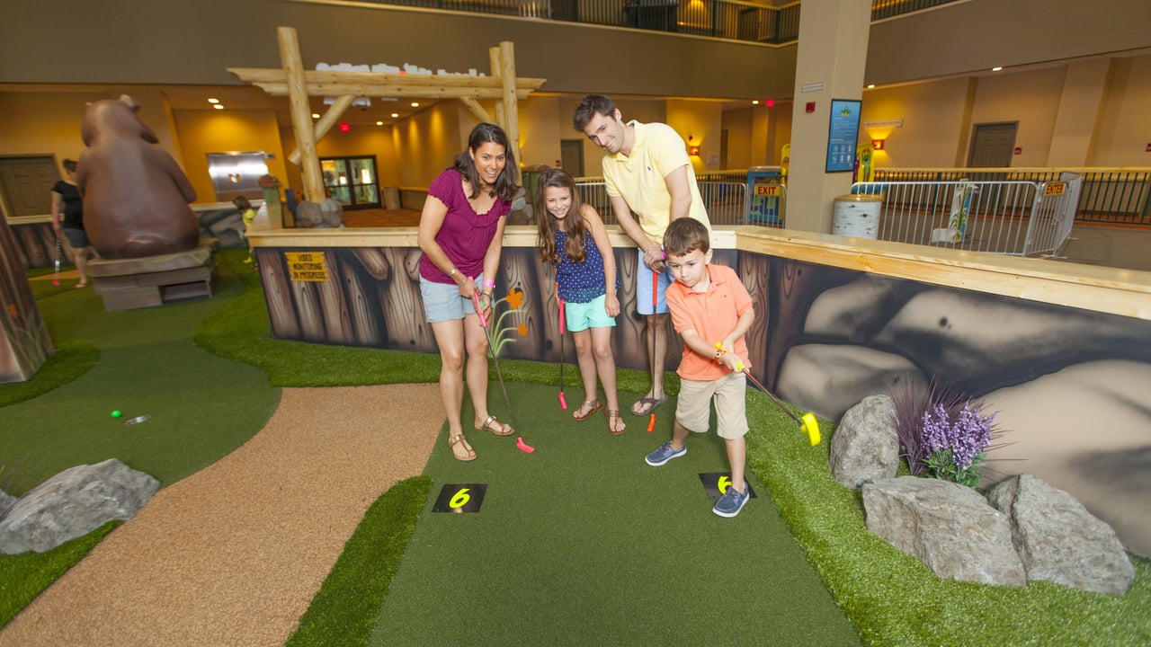 Family playing indoor golf and ateempting putt together