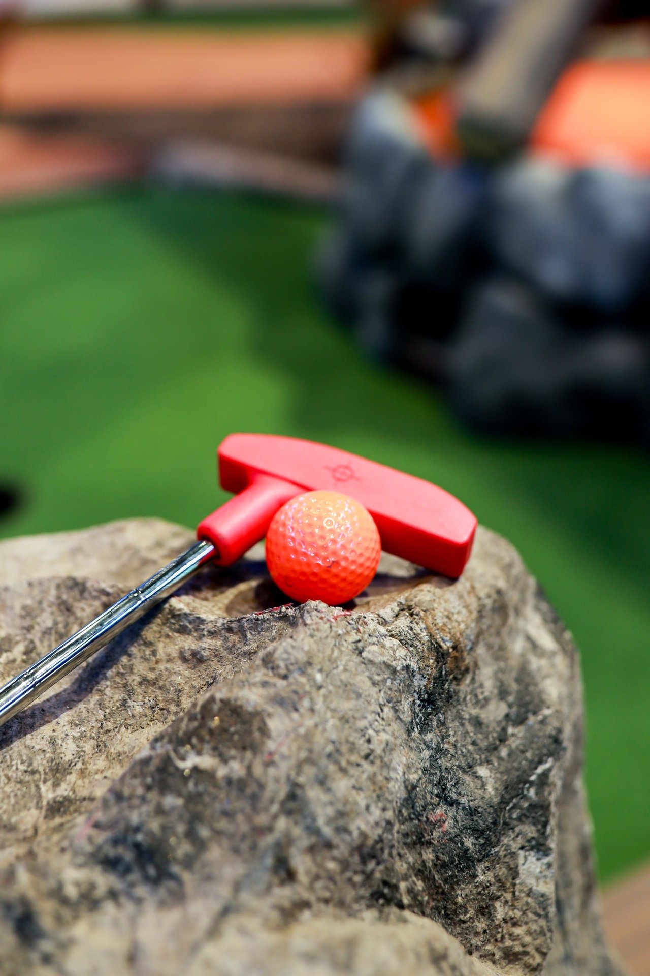 A pink club and pink ball on a rock