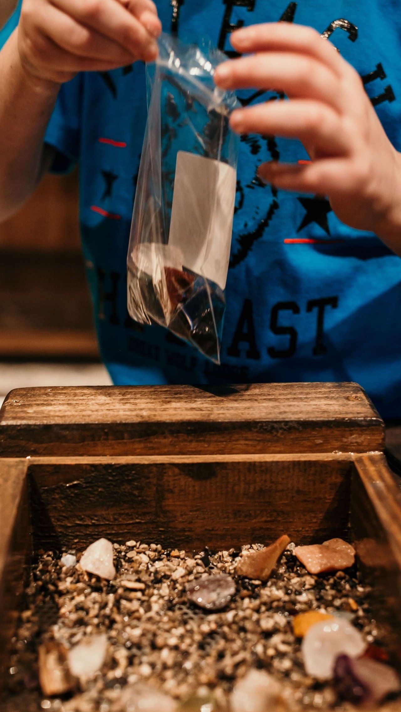 Child collecting gemstones in plastic bag indoors