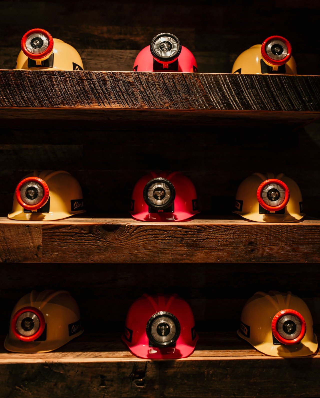 Rows of yellow and pink mining helmets on a shelf