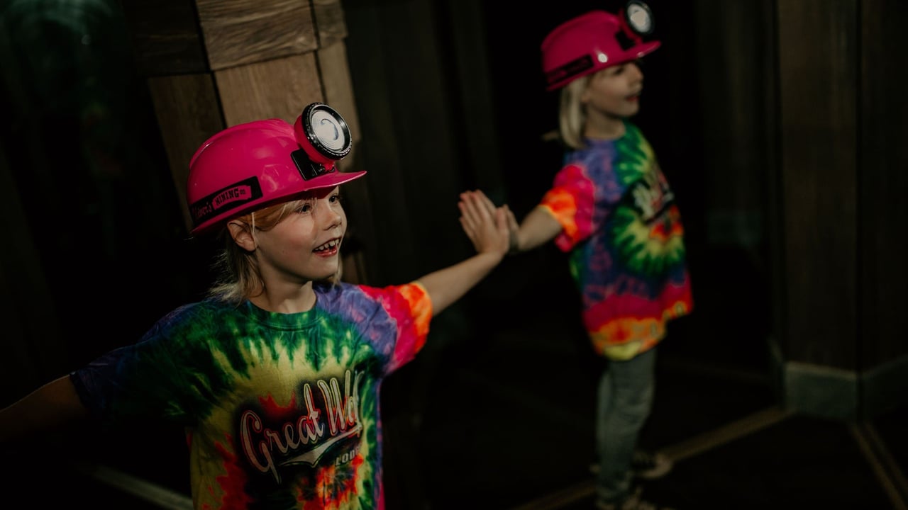 Child in pink helmet smiling and posing in mirror maze