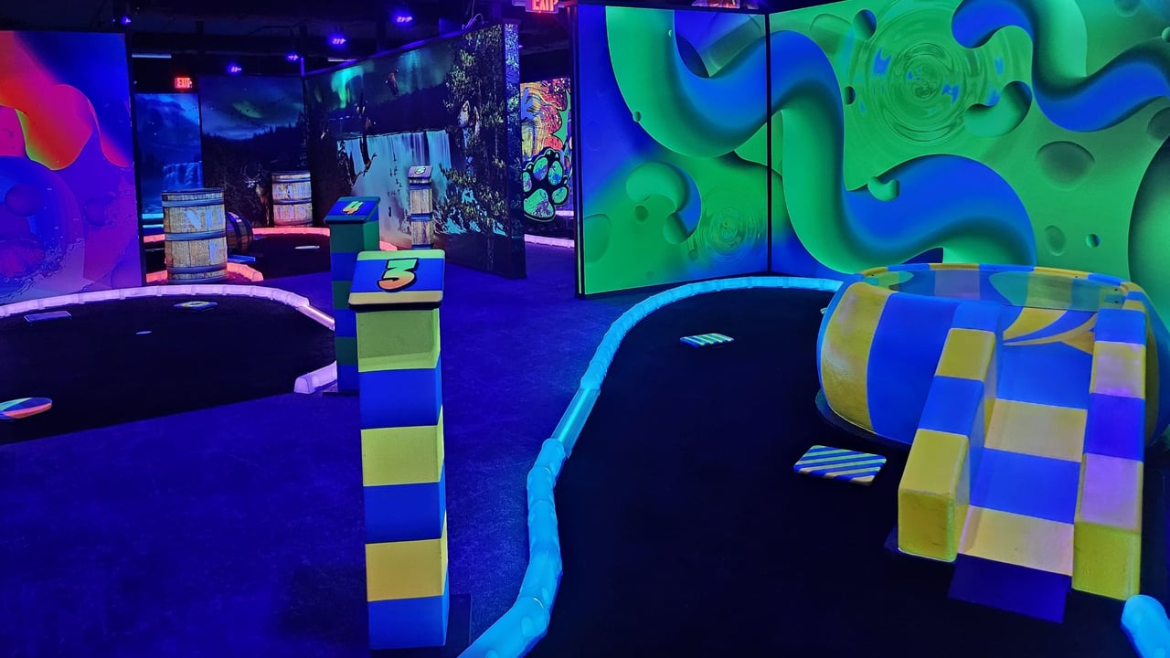 Glow-in-the-dark mini golf course with vibrant walls