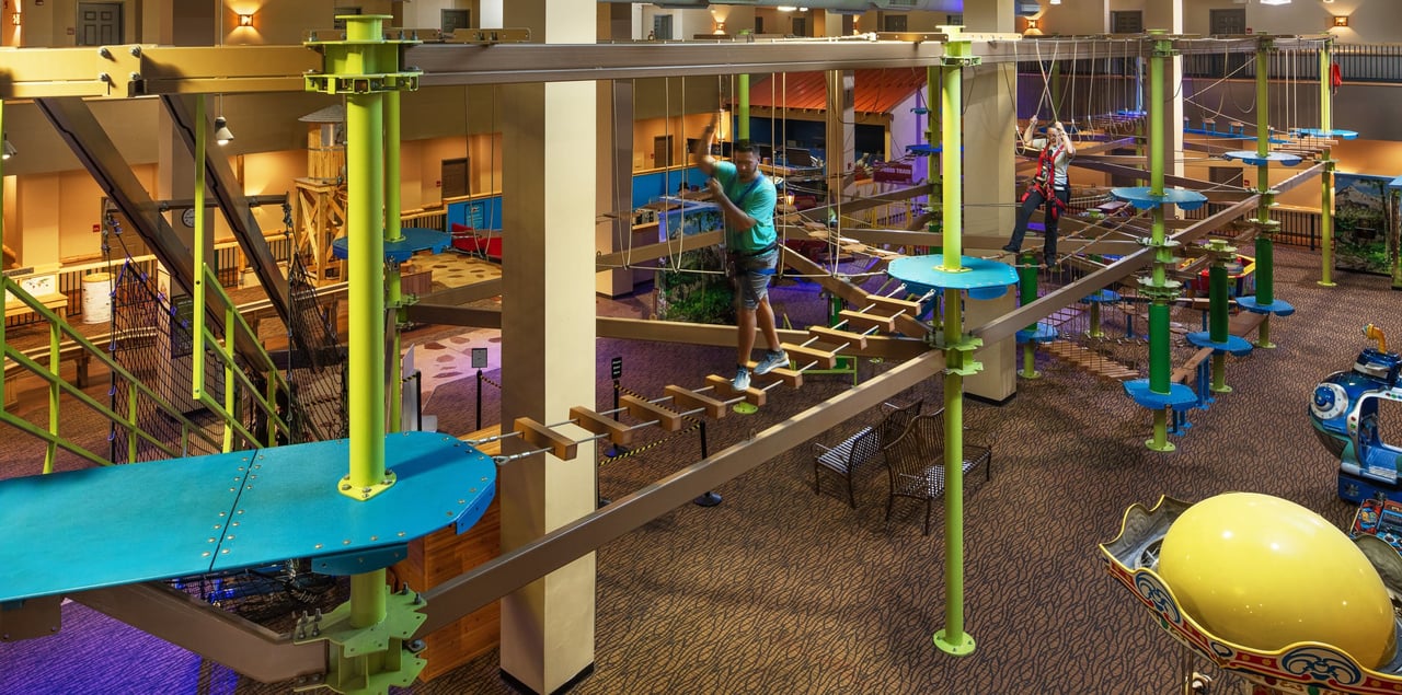 A man and a woman climbing the ropes course