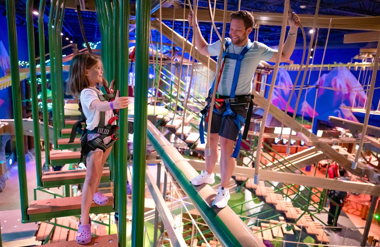 Man and his daughter are climbing the ropes course