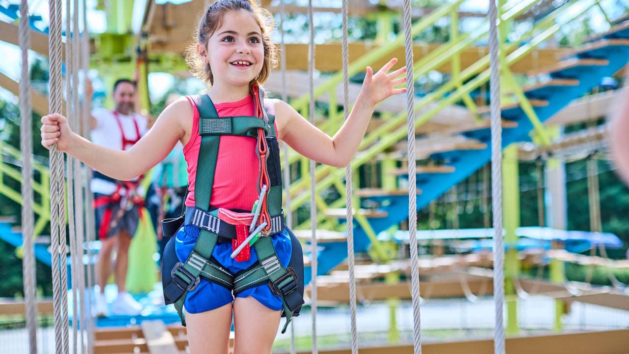 Smiling girl in harness on a rope bridge