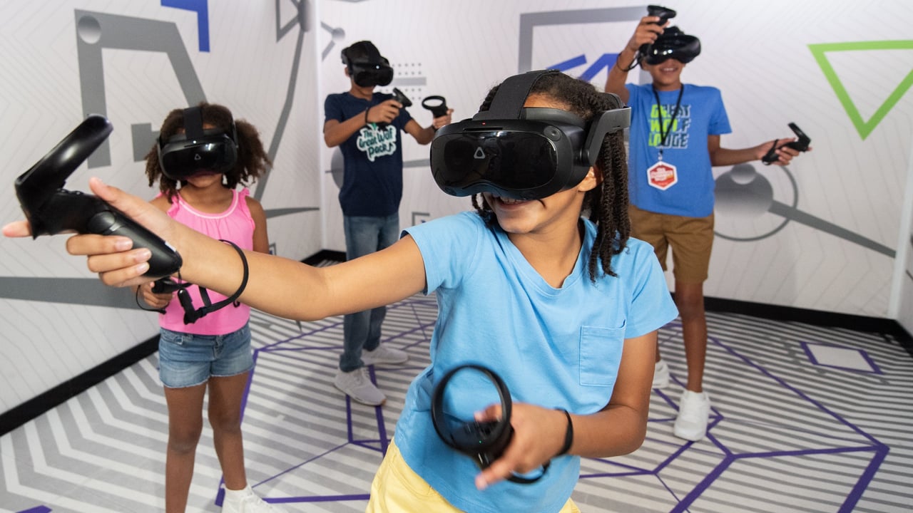 Kids wearing VR headsets play with controllers indoors