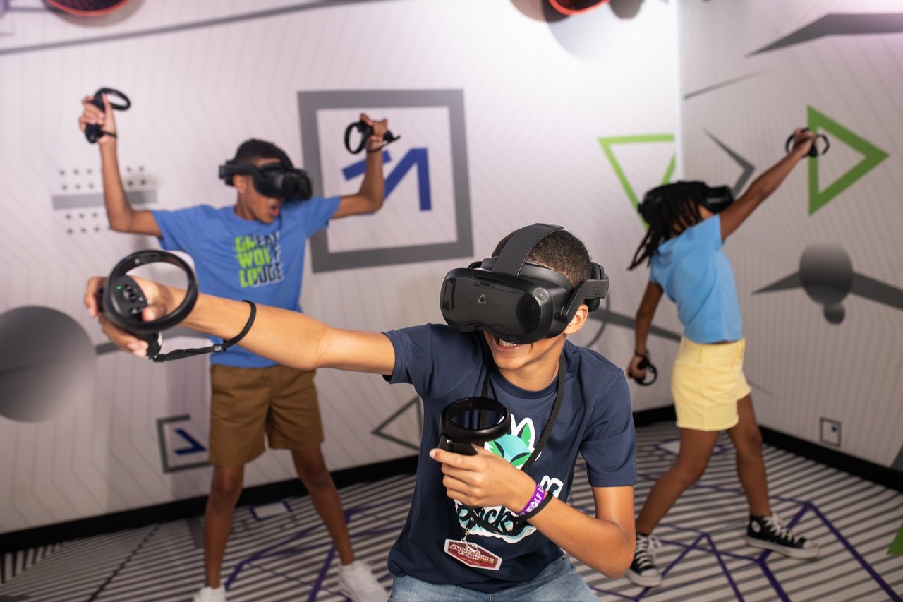 Group of kids playing an energetic VR game with headsets and controllers