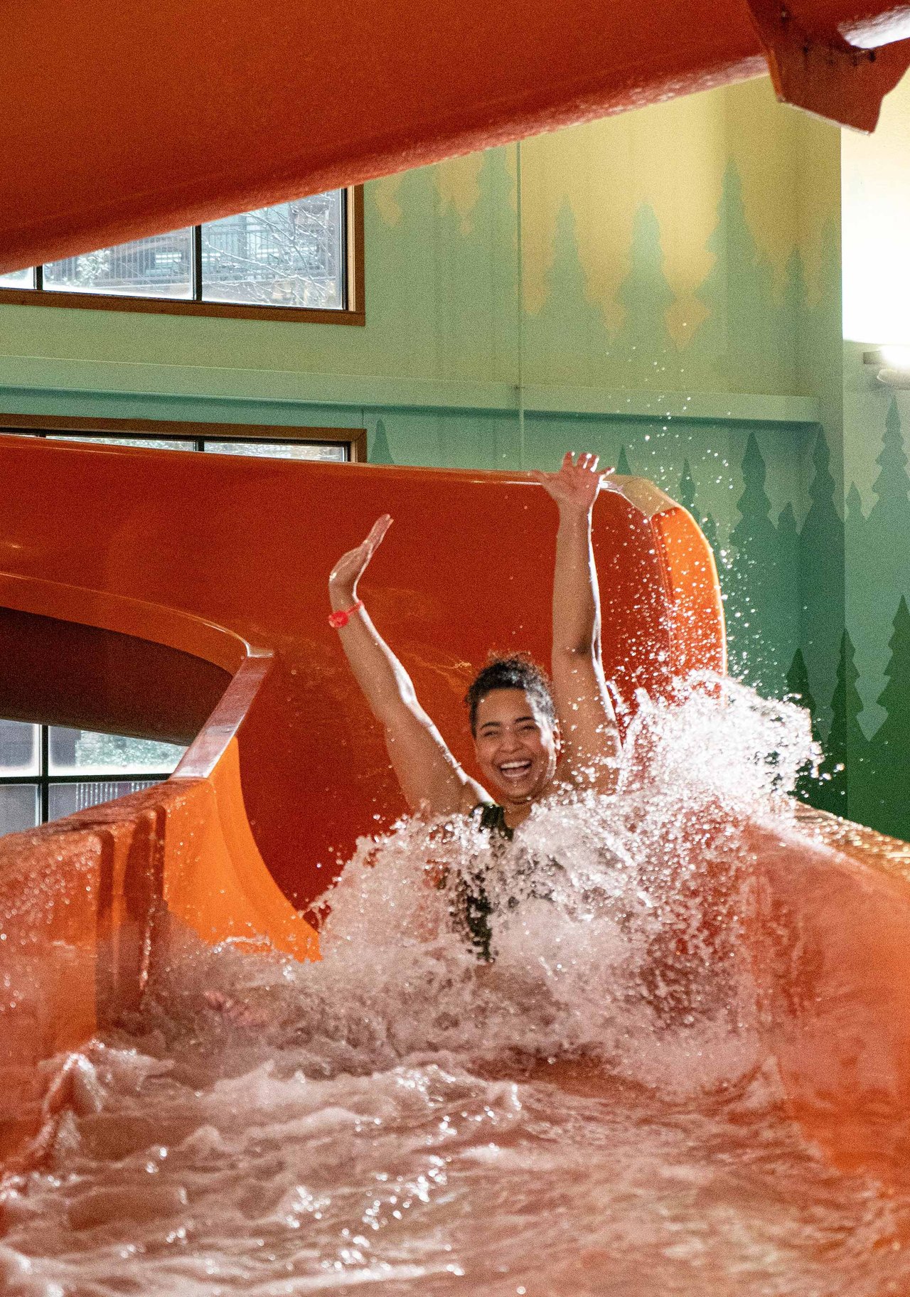 A woman with her arms up going down an orange water slide