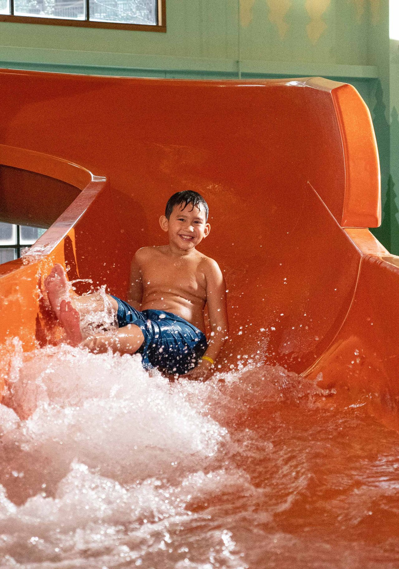 A young boy going down an orange water slide