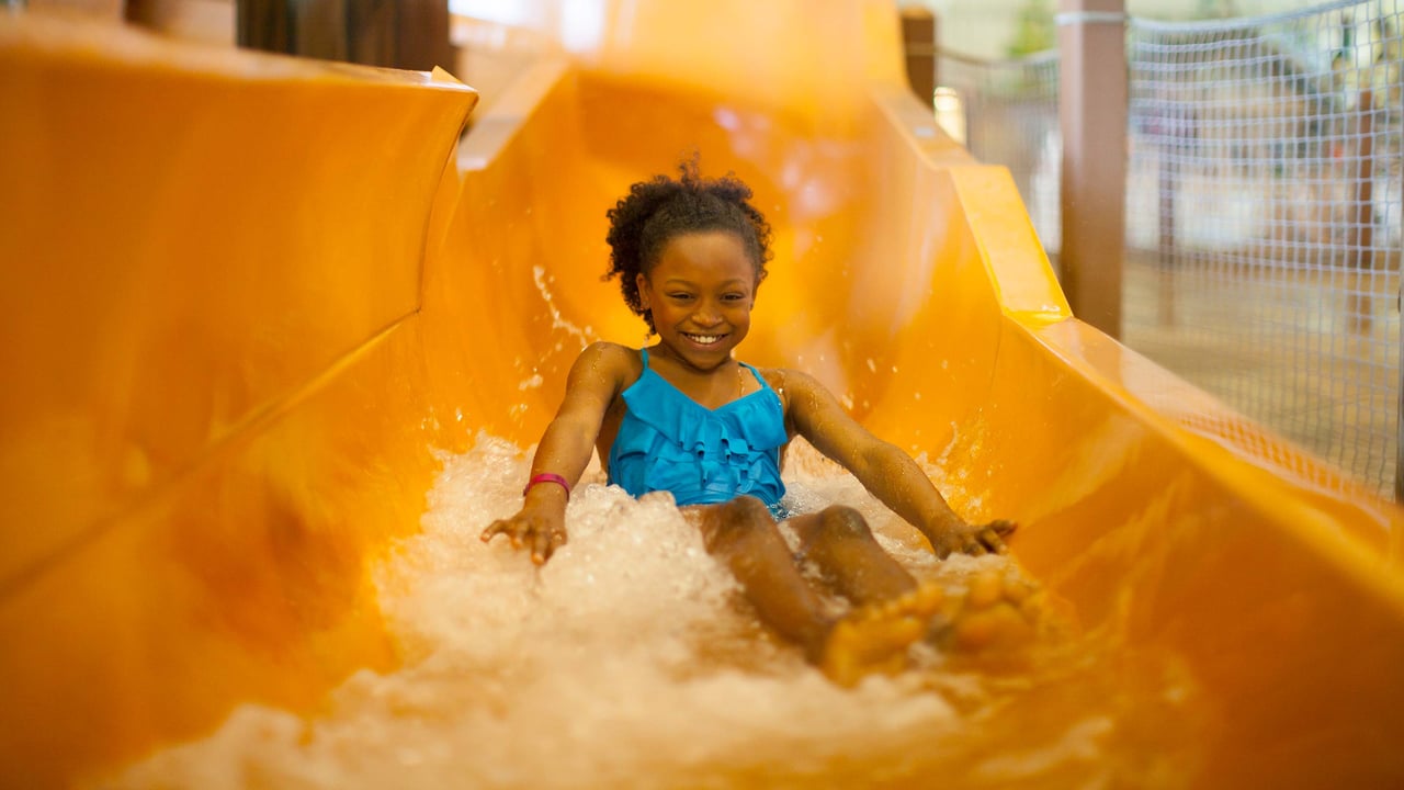 A young girl going down an orange water slide