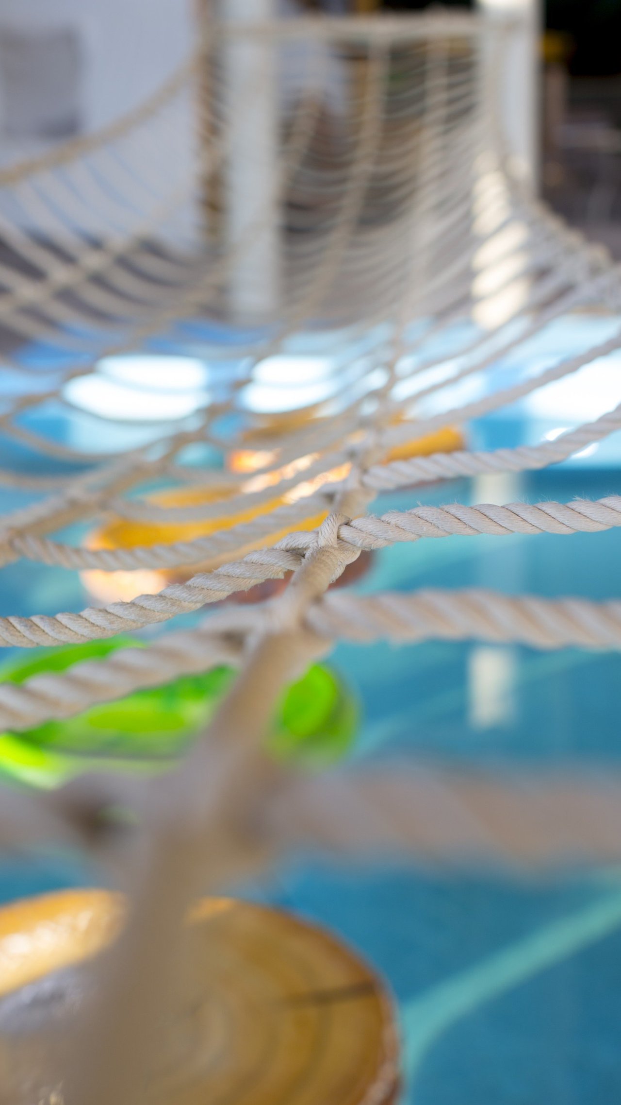 A view of the rope bridge going over the pool above the lily pad floats 