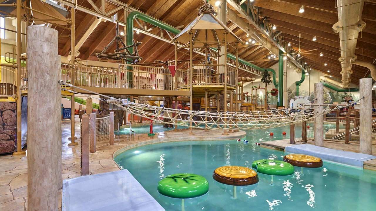 A view of the rope bridge going over the pool above the lily pad floats 