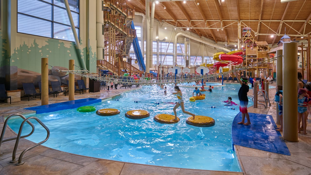 A large indoor water park featuring multiple colorful slides and a spacious pool area filled with families enjoying the attractions.