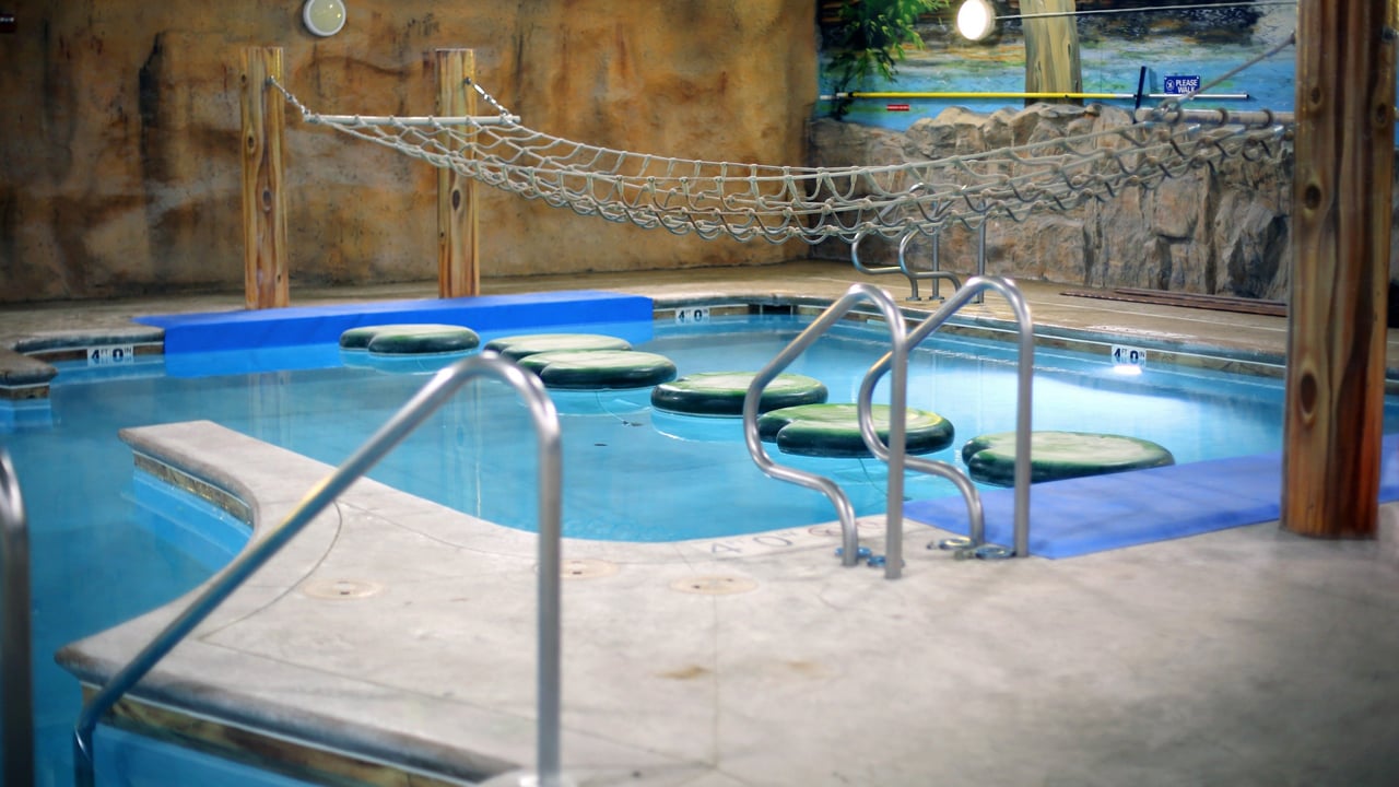 A sunny pool scene with a rope swing hanging over the water and a bright slide for thrilling splashes.