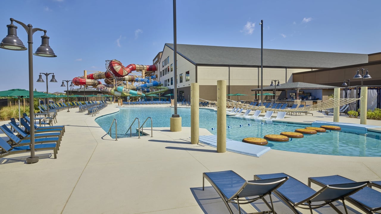 A vibrant pool area with comfortable chairs and a fun water slide, perfect for relaxation and recreation.