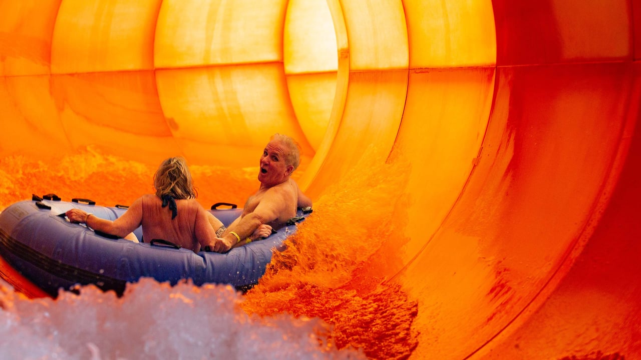 elderly couple enjoying a raft slide in an indoor water park