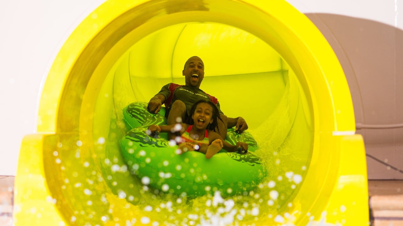 Father and daughter in a tube racing down a yellow waterslide