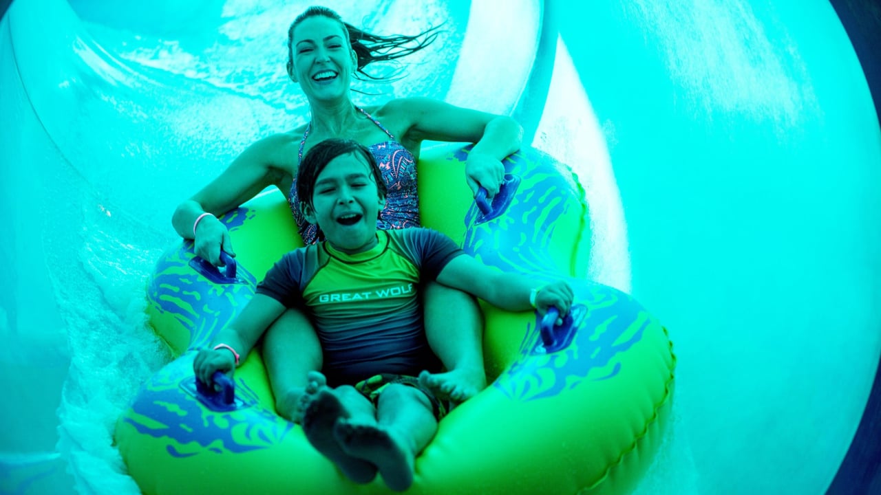 Mother and son racing down a blue water slide