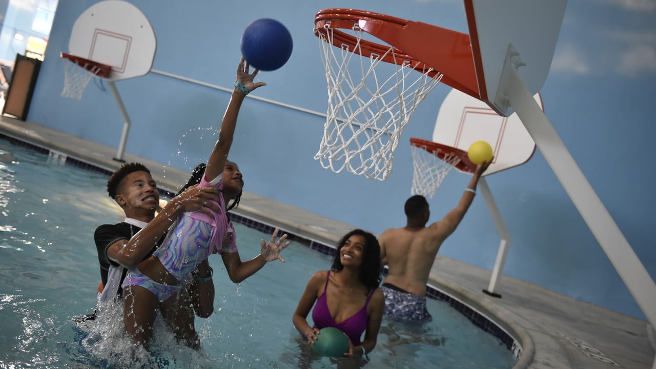 family playing basket ball in an indoor pool