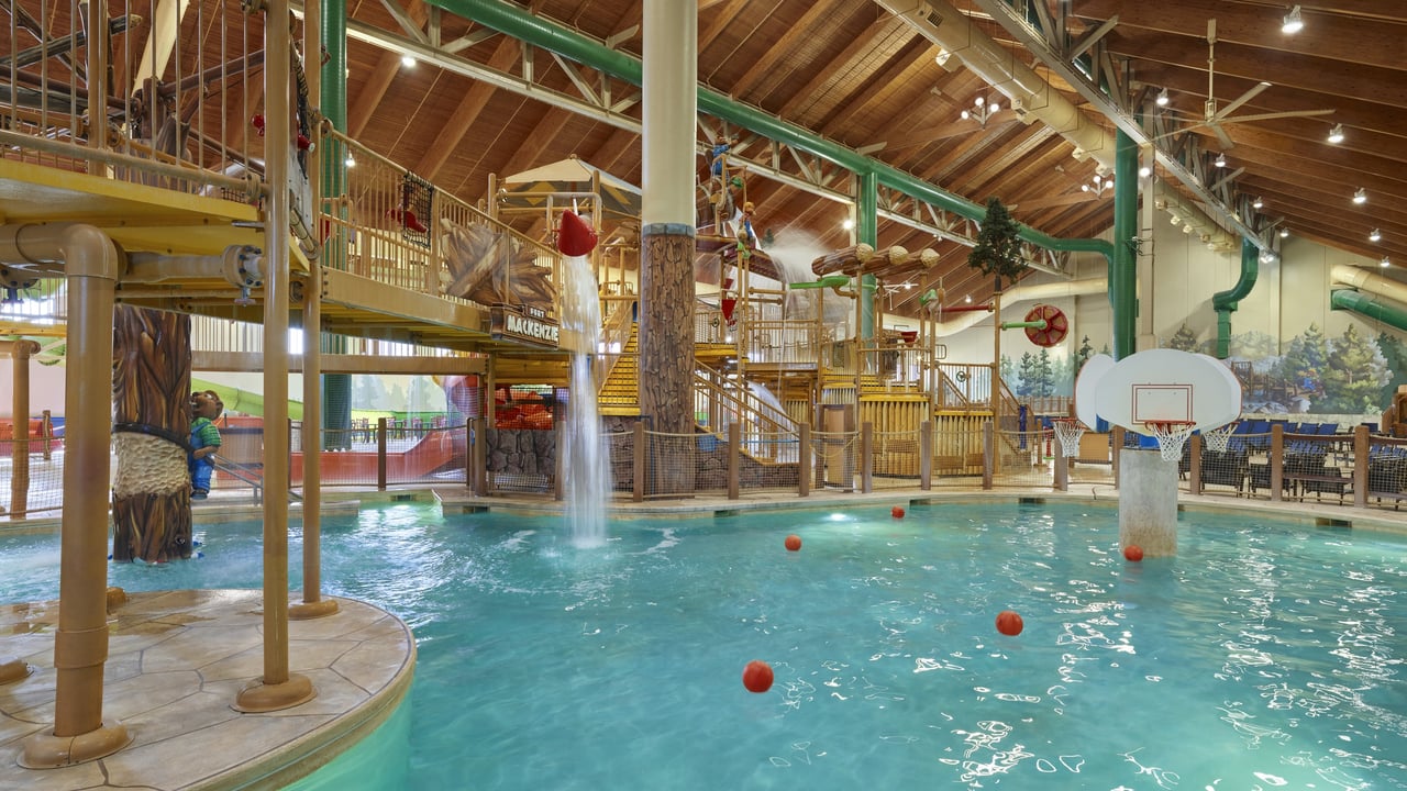 A spacious indoor pool featuring a basketball hoop above the water