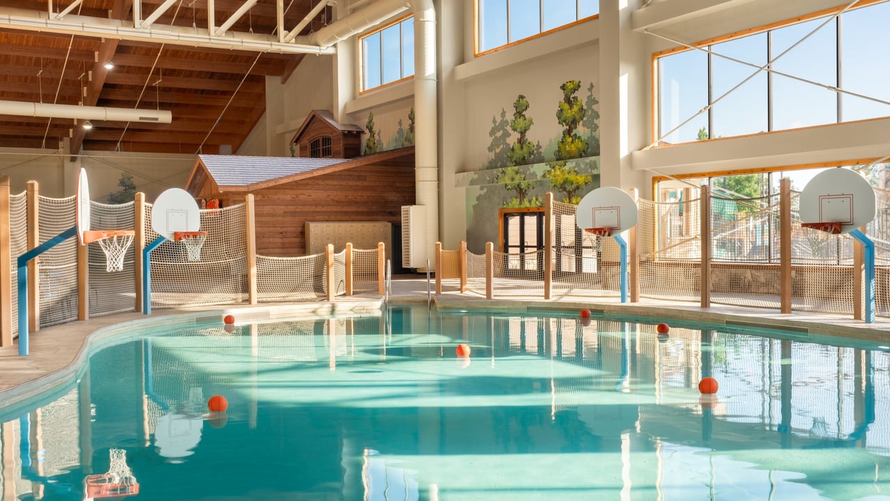 A spacious indoor pool featuring basketball hoops above the water